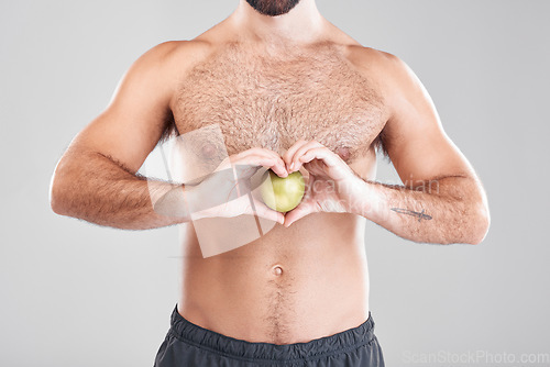 Image of Man, fitness and heart hands with apple in studio isolated on a gray background. Food, wellness and male model with love hand gesture, fruits for nutrition or healthy diet, vitamin c or minerals.