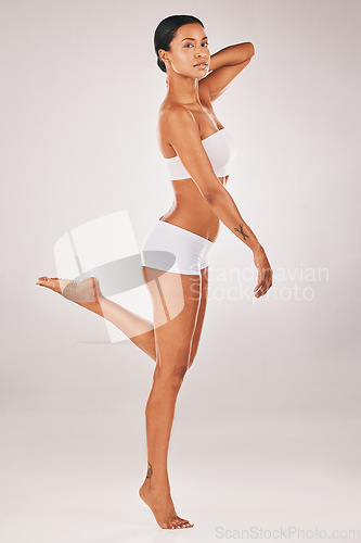 Image of Portrait, body and balance with a model black woman in studio on a gray background for natural beauty. Fitness, wellness and underwear with an attractive young female posing to promote health