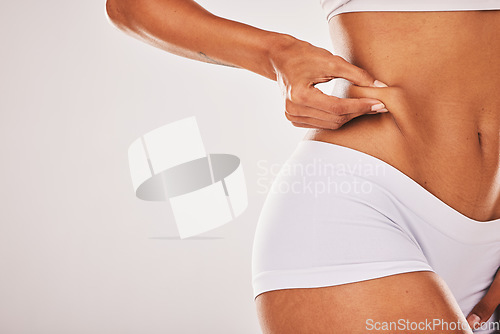 Image of Fat, weight and woman touching her stomach isolated on a grey studio background with mockup space. Skin, cellulite and hands of a model feeling her body for insecurity, health and tummy tuck