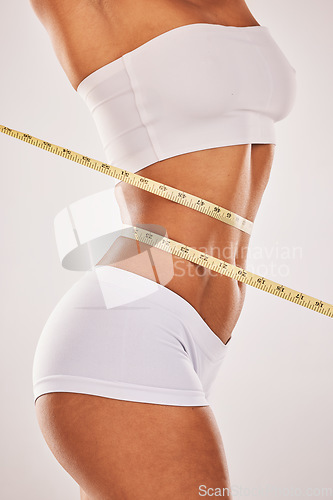 Image of Lose weight, body and woman with tape measure on stomach for diet, health and wellness. Healthy model studio background for fitness, goal and motivation in underwear for exercise results and progress