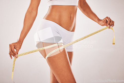 Image of Woman, body and lose weight with tape measure on thigh for healthy diet, health and wellness. Model studio background for fitness, goals and motivation in underwear for exercise results and progress