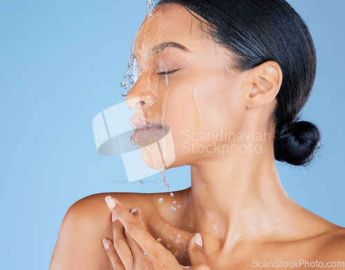 Image of Beauty, water splash or washing face in shower grooming, healthcare or sustainability cleaning on isolated blue background. Zoom, black woman or model in wet drops for skincare hydration dermatology