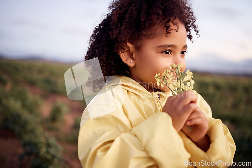 Image of Children, farm and a girl smelling a flower outdoor in a field for agriculture or sustainability. Kids, nature and spring with a female child holding flowers to smell their aroma in the countryside