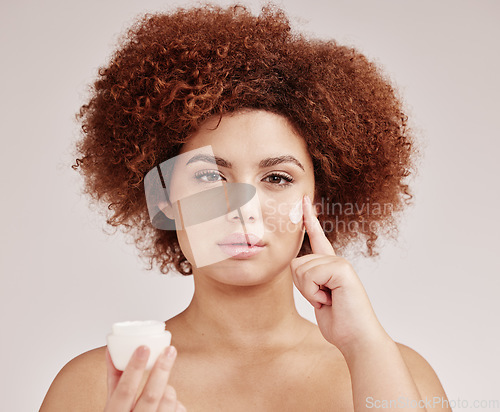 Image of Skincare, beauty and portrait of black woman with lotion on face, afro and advertising luxury skin product promotion. Dermatology, cosmetics and facial, model with jar isolated on studio background.