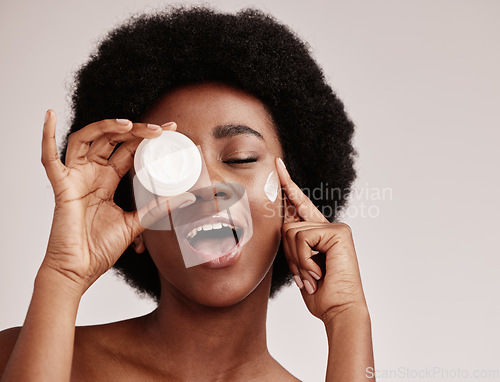 Image of Skincare, beauty and black woman holding cream on face, afro and excited advertising luxury skin product promotion. Dermatology, spa cosmetics and facial for happy model isolated on studio background