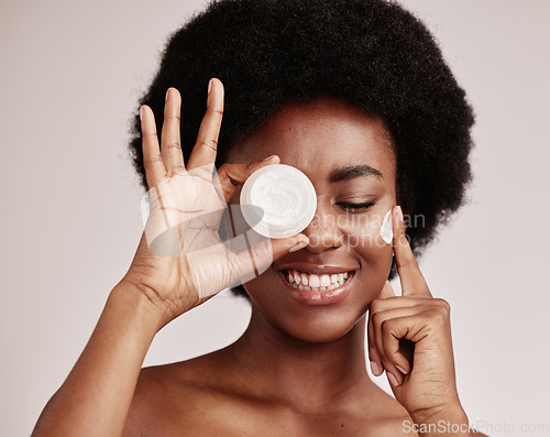 Image of Skincare, product and black woman with cream on face, afro and excited advertising luxury skin care promotion. Dermatology, spa cosmetics and facial for happy model girl isolated on studio background