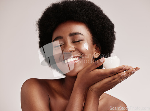 Image of Skincare, smile and black woman holding cream on face, afro and excited advertising luxury skin product promotion. Dermatology, spa cosmetics and facial for happy model isolated on studio background.