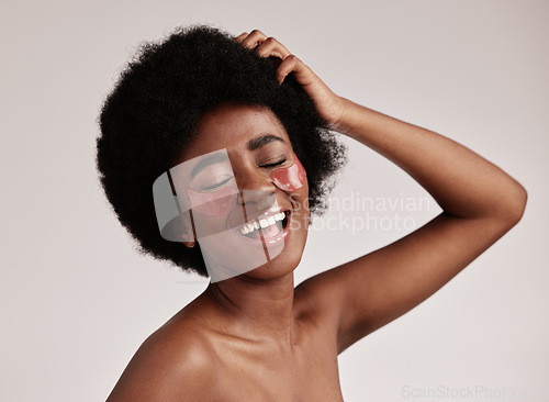 Image of Skincare, beauty and black woman with collagen eye patches for anti ageing treatment isolated on grey background. Health, skin and model with afro, smile and face mask on eyes, spa facial in studio.