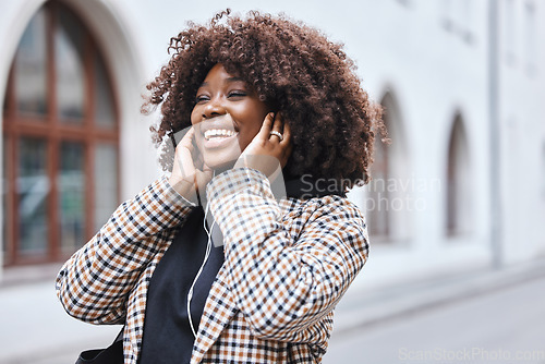 Image of Black woman, earphones and listening to music in the city streets with smile for entertainment. Happy African American female walking in a urban town smiling in joyful happiness for audio sound track