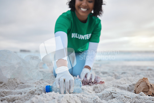 Image of Hand, bottle and a volunteer woman on the beach for community, charity or activism during a clean up. Cleaning, environment and plastic with a female picking up plastic litter or polution on a coast