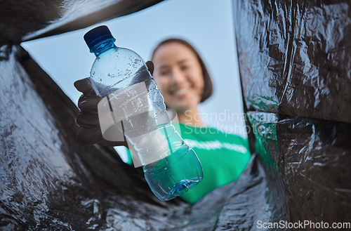 Image of Recycling, bottle and woman with view in bag, sustainability and cleaning plastic pollution, earth day and community service. Saving the environment, charity and people putting trash in garbage bin