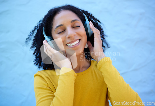Image of Black woman, music headphones and smile on wall background, blue backdrop or outdoor. Happy girl listening to radio, podcast and sound of streaming, audio or face of happiness, relax or hearing tech