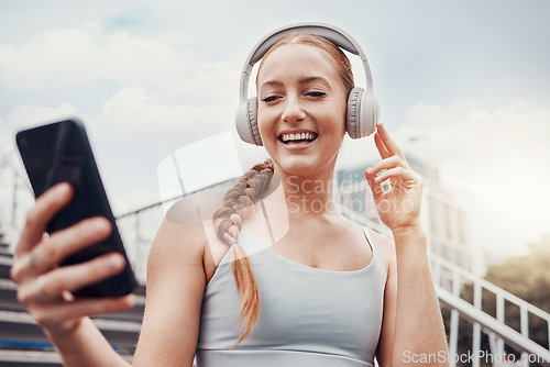 Image of Fitness, woman and phone with headphones in the city for music listening, 5G connection or workout motivation. Happy female runner smile for headset, smartphone or audio track for exercise on stairs