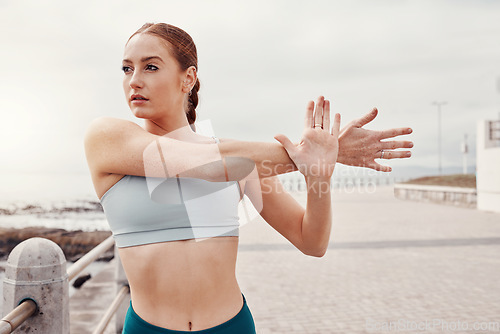 Image of Fitness, sports and woman stretching arms in city for motivation, warm up and start cardio workout by sea. Running, exercise and girl focus for healthy body, wellness and marathon training by ocean