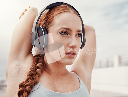 Image of Stretching, fitness and face of woman with headphones listening to music, podcast and audio for warm up. Running, sports and girl start workout, wellness exercise and marathon training in urban city