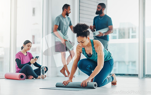 Image of Yoga, fitness and a black woman rolling her mat on the floor of a studio for exercise or wellness. Gym, workout and health with a female yogi in the gym for pilates training or spiritual wellbeing