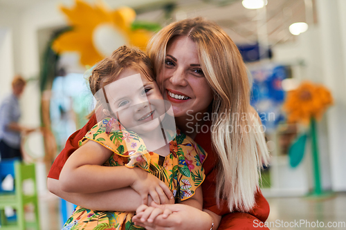 Image of A cute little girl kissing and hugs her mother in preschool