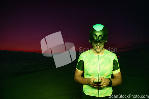 Image of A triathlete using a smartphone while taking a break from a hard night's cycling training