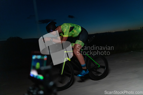 Image of A videographer recording a triathlete riding his bike preparing for an upcoming marathon.Athlete's physical endurance and the dedication required to succeed in the sport.