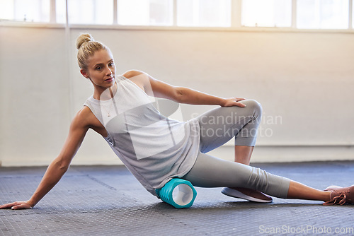 Image of Fitness, physio and pilates, woman with roller on floor for leg tension and support in yoga workout at gym. Health, sports and massaging for physiotherapy massage, girl on ground foam rolling muscle.