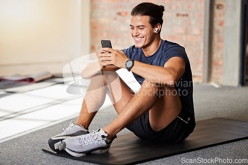 Image of Bodybuilder, gym floor and texting with smile on chat app, social media or meme on internet for happiness. Man, fitness and exercise for health, wellness or relax at training for online communication