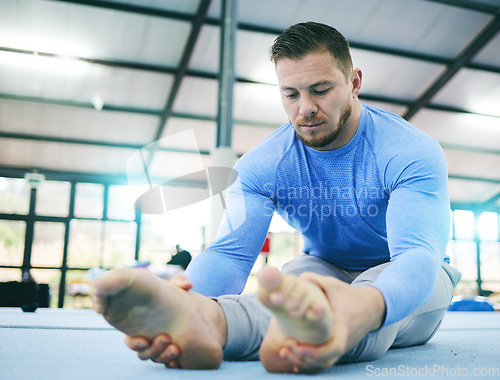 Image of Gymnastics, exercise or man stretching legs in gym before training, workout or health wellness. Focus, serious fitness or sport athlete doing pilates, meditation or zen balance in sports studio floor