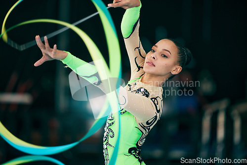 Image of Sports, gymnastics and female performing with a ribbon for a competition or training in sport arena. Fitness, athlete and woman practicing for balance, endurance and flexibility exercise for routine.