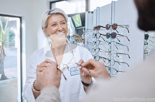 Image of Glasses, retail store and sale of a senior eye doctor holding a frame to help customer shopping. Happy optometrist, shop wellness and service of an elderly eyes expert with eyeglasses vision check