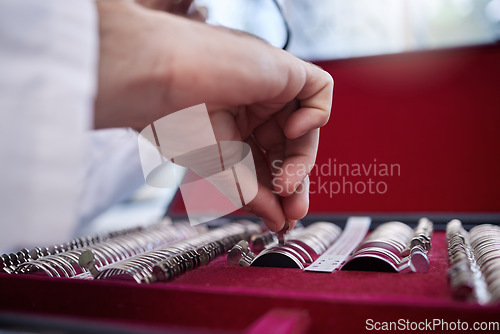 Image of Optometry, test lens kit and hand of a optometrist preparing for a eye exam in a optical health clinic. Vision, diopter glasses and eyecare doctor or oculist fixing prescription lenses in optic store