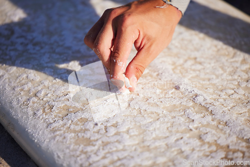 Image of Hand, surfboard and wax with a sports man outdoor at the beach for surfing or recreation during summer. Fitness, surf and maintenance with a male surfer or athlete outside on the coast for surfing