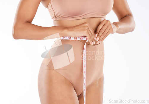 Image of Tape, fitness body and woman isolated on a white background for lose weight or tummy tuck in underwear. Model person in lingerie, measure waist or stomach for liposuction results or health in studio