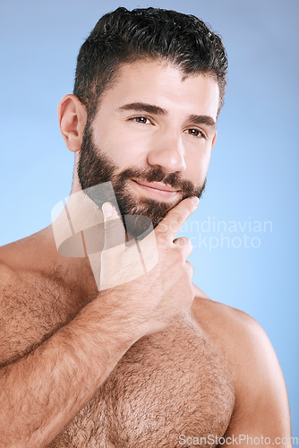 Image of Idea, beauty and skincare with a man model in studio on a blue background for natural wellness or grooming. Face, beard and skin with a handsome young male thinking about cosmetics or treatment