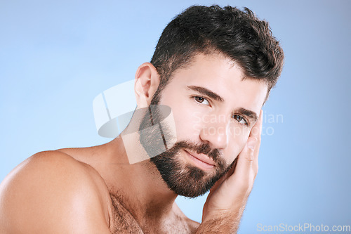 Image of Skincare, glow and portrait of a man feeling face isolated on a blue background in a studio. Beauty, clean and model touching facial beard, grooming and cleaning for dermatology treatment on backdrop