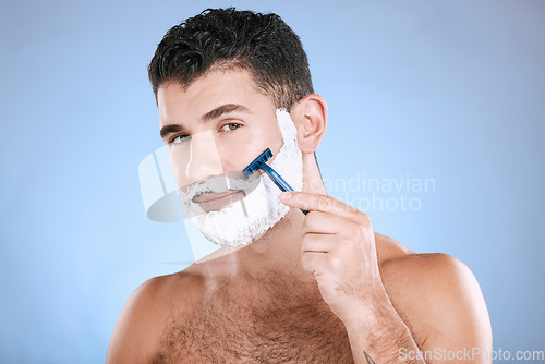 Image of Shaving, grooming and portrait of a man with cream for beard isolated on a blue background. Skincare, beauty and model with razor to shave hair on face with foam for a clean facial look on a backdrop