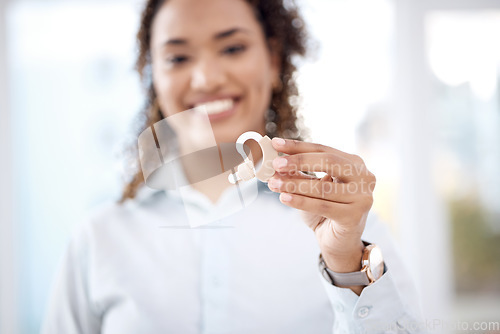 Image of Hand, hearing aid and insurance with a black woman holding a listening device in a healthcare clinic. Medical, technology and audiology with a female medicine professional standing in a hopsital