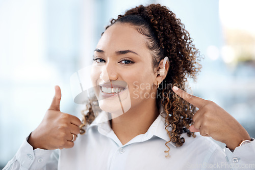 Image of Thumbs up, happy and portrait of a woman with a hearing aid pointing to her ear in the office. Happiness, success and young professional female with a deaf piece and a approval gesture in workplace.