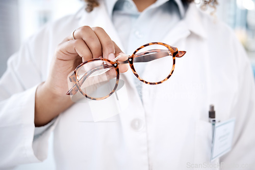 Image of Glasses, hand and vision with a doctor woman holding a pair of frame eyewear in a clinic for sight correction. Healthcare, medical and insurance with a female optometrist showing prescription lenses