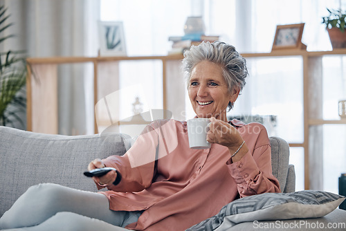 Image of Senior woman, sofa and coffee to relax with remote for television, video or movies with smile in house. Elderly lady, couch and tea with happiness in home living room for watching tv in retirement