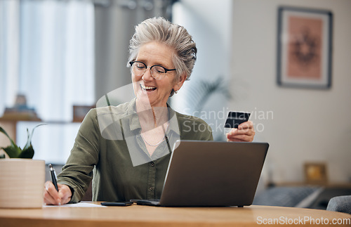 Image of Laptop, credit card and senior woman paying her bills, debt or mortgage with online banking. Elderly lady planning a financial investment or calculating her retirement finances on paper at her home.