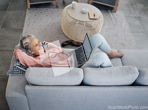 Image of Laptop, phone call and senior woman on a sofa with a remote job working on a project at her home. Happy, laugh and elderly female on a mobile conversation while on a computer in her living room.