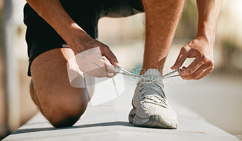 Image of Fitness, shoes and laces with a man runner getting ready for a cardio or endurance workout closeup outdoor. Exercise, running and workout with a male athlete fastening shoelaces while training