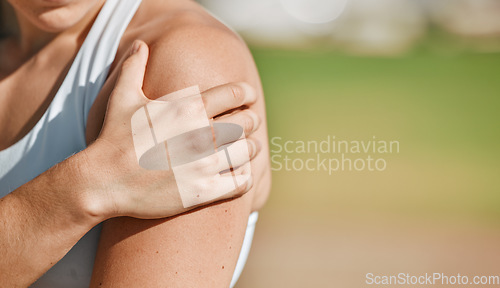 Image of Hand, arm or injury with a sports woman holding her shoulder in pain outdoor next to mockup space. Fitness, medical and anatomy with a female athlete suffering with an injured joint or muscle outside