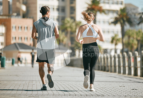 Image of Fitness, teamwork or coaching with a runner couple on the promenade for cardio or endurance from the back. Exercise, wellness or workout with a man and woman athlete running outdoor in the city