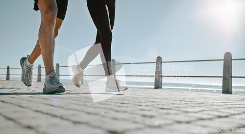 Image of People, legs and running at the beach for exercise, cardio workout or training together outdoors. Leg of friends taking run, walk or jog on warm sunny day by the ocean coast for healthy wellness