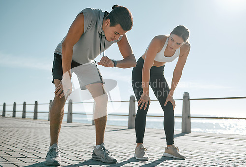 Image of Tired couple, fitness and exercise time for performance or progress with blue sky at sea outdoor. Woman and man check watch mobile app in nature for workout, running and healthy lifestyle in summer