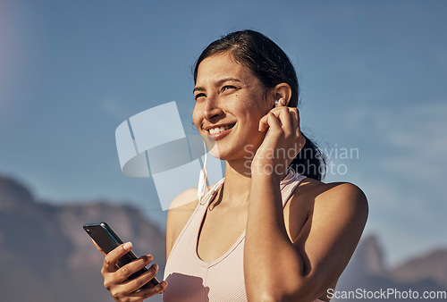 Image of Woman, fitness and phone for music in nature outdoor for exercise, training and workout. Happy model person listening to earphones for podcast, audio and motivation for health and wellness blue sky