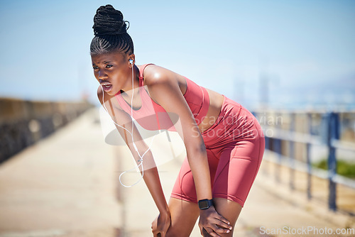 Image of Tired black woman breathing outdoor for fitness, healthy target and body fatigue. Female athlete, break and breathe for sports workout, running exercise and music earphones of city training challenge