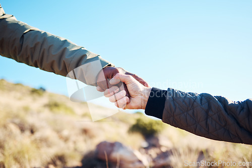 Image of Friendship, help and men holding hands on a hike for support while climbing a rock on a mountain. Assistance, adventure and interracial male friends trekking together for fitness challenge in nature.