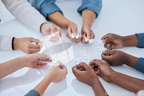 Image of Business people, hands and puzzle in team building for planning, strategy or collaboration above on table. Hand of group in teamwork solution or support for project management and cooperation at work