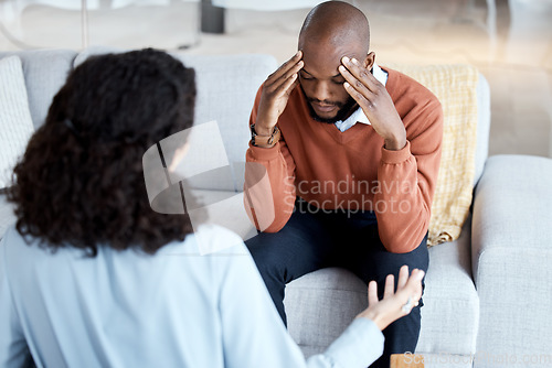 Image of Black man, mental health and counseling with woman psychologist, stress headache and depression with help. Consultation, doctor with patient and conversation about anxiety problem, sad and depressed